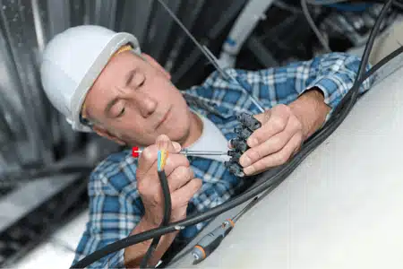 Electrician inspects ceiling wires to assess when should you rewire a house for safety