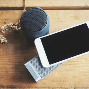 A smartphone beside compact wireless speakers, often rated among the best home gym speakers