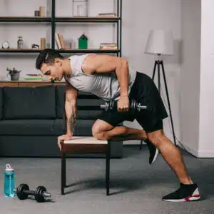 Man lifting dumbbells in a home gym where best home gym speakers enhance the workout