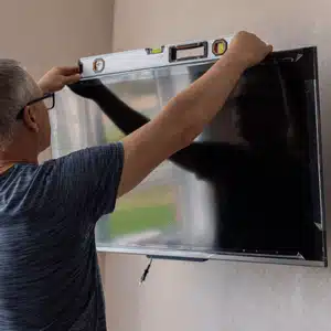 Tv mount professionals carefully level the screen for perfect viewing and stable wall installation