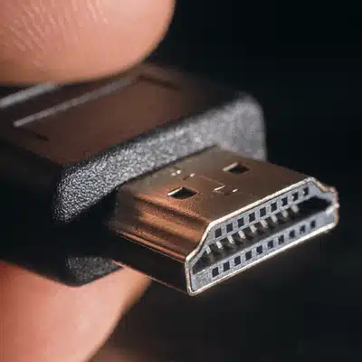 Close-up image of a hand holding an HDMI connector used for audio and video transmission