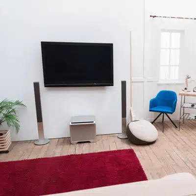 Modern living room with wall-mounted TV and floor speakers arranged symmetrically for immersive sound enjoyment