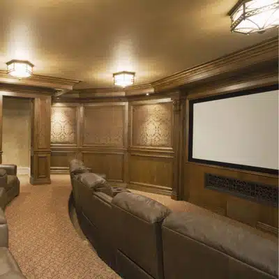 Luxurious wood-paneled home theater with recliners, large screen, and warm ceiling lights for private screenings
