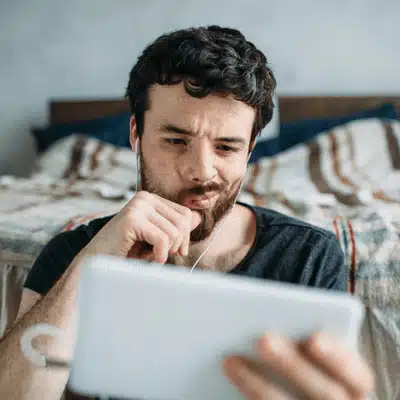 Man watches tablet with earphones, frowning about smart home challenges, troubleshooting device connectivity issues today