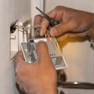 Technician wires wall controller during setup, delivering reliable home automation installation services for homeowners today