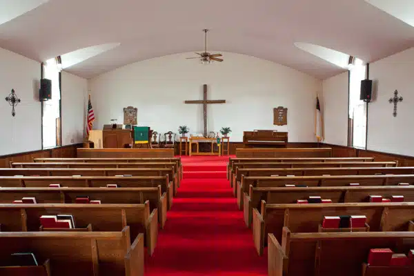 Empty church sanctuary with pews, red aisle carpet, and altar; church sound system installation view