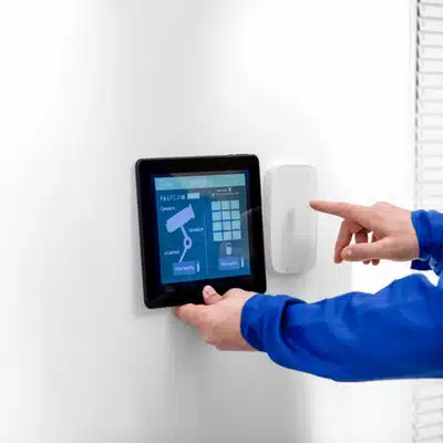 Photo shows technician adjusting wall-mounted smart home control panel configured by home technology integrators today