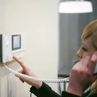 Resident uses corded indoor screen to call visitors; residential intercom system enables two-way entry talk