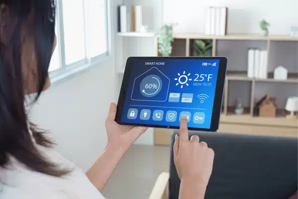 Person uses tablet to control smart home settings, comparing Wireless home intercom systems for indoor communication